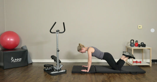 a woman is working out on yoga mat beside Sunny stepper