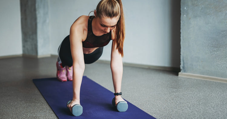 a woman is planking with dumbbells