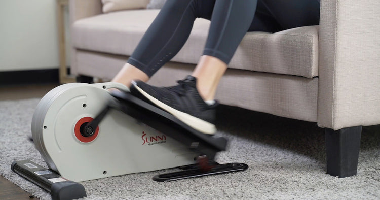 Sunny trainer pedaling under desk elliptical