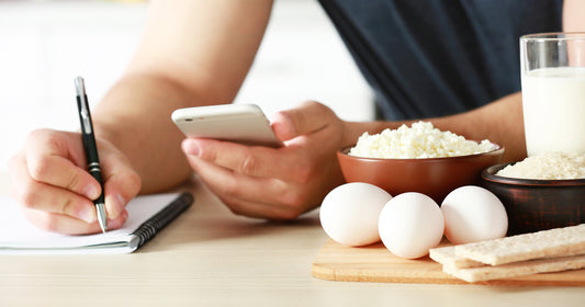 a man is holding a pen and a phone to count calories of food