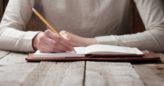 a man is holding a pen and writing on notebook