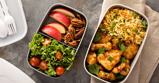 two boxes of lunch with fruit, vegetable, and protein