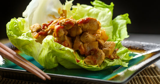 a chicken wrap on a plate with chopsticks aside