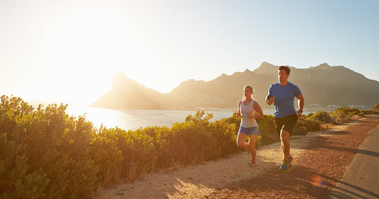 two people are running in a lake park under sunshine