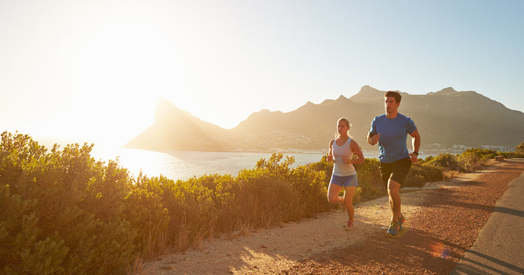 two people are running in a lake park under sunshine