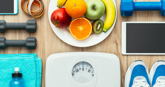 a plate of fruit, scale, dumbbells, shoes, and pad in alignment